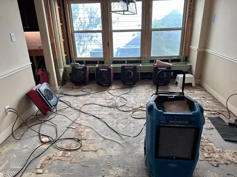 Dehumidifier and a row of air movers drying a breakfast nook with the flooring pulled up